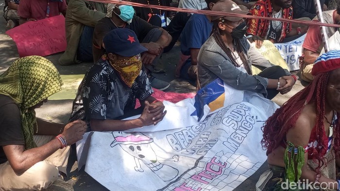 Mahasiswa Papua membawa spanduk bergambar One Piece saat demo di Makassar.