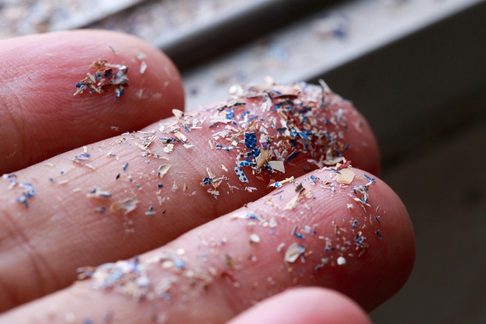Foto close-up dari samping mikroplastik yang menempel di tangan manusia. Konsep polusi air dan pemanasan global. Ide perubahan iklim.