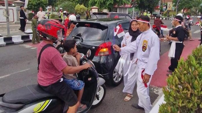 Satlantas Polres Sragen bersama FKPPS saat membagikan bunga dan bendera Merah Putih kepada pengguna jalan di simpang empat Alun-alun Sragen.