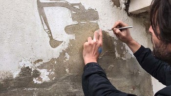 Seniman sedang membuat mural dengan cara diukir. Foto: via BoredPanda
