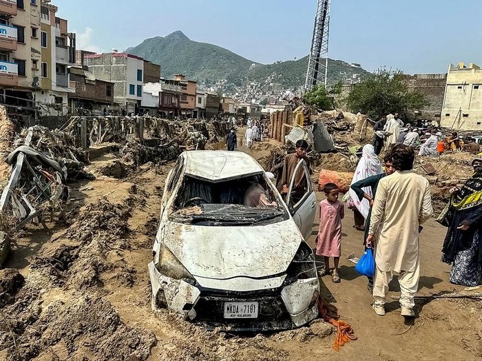 People gather near a damaged vehicle and scattered debris after the road washed out following a flash flood in Mingora, the main city of Swat Valley, in monsoon-hit northern Pakistans mountainous Khyber Pakhtunkhwa province on August 16, 2025. The death toll from heavy monsoon rains that have triggered flash floods across northern Pakistan has risen to at least 321 people in the last 48 hours, disaster agencies said on August 16. (Photo by Mehboob UL HAQ / AFP)
