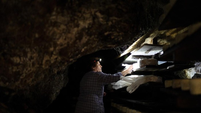 Cheesemaker Encarnacion Bada tends to Cabrales blue cheese inside a maturing cave near Tielve, northern Spain, August 7, 2025. Women like Encarnacion Bada have long upheld the artisanal tradition of crafting Cabrales by hand and aging it in mountain caves, a practice now at risk as younger generations move away. REUTERS/Bernat Parera