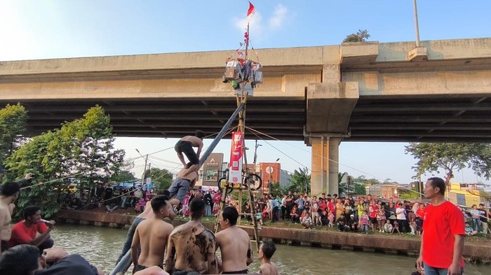 Lomba panjat pinang di Kalimalang, Jakarta Timur, meriahkan Hari Kemerdekaan RI ke-80. (Kurniawan/detikcom)