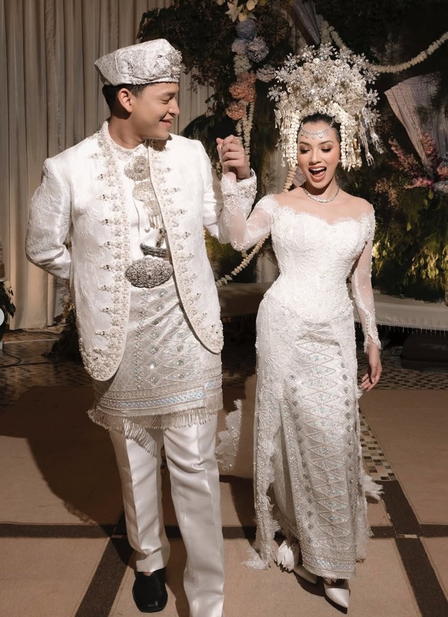 Nazla tampil cantik dan anggun kenakan kebaya putih modern dengan detail renda, payet, dan manik-manik, yang dipadukan dengan bawahan songket khas Minang. Penampilannya serasi dengan Adikara yang mengenakan baju adat Minang bernuansa putih keperakan dengan bordiran detail dan hiasan payet yang membuatnya tampak megah. Foto: Instagram/@nazlaalifa