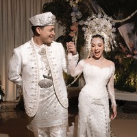 Nazla tampil cantik dan anggun kenakan kebaya putih modern dengan detail renda, payet, dan manik-manik, yang dipadukan dengan bawahan songket khas Minang. Penampilannya serasi dengan Adikara yang mengenakan baju adat Minang bernuansa putih keperakan dengan bordiran detail dan hiasan payet yang membuatnya tampak megah. Foto: Instagram/@nazlaalifa