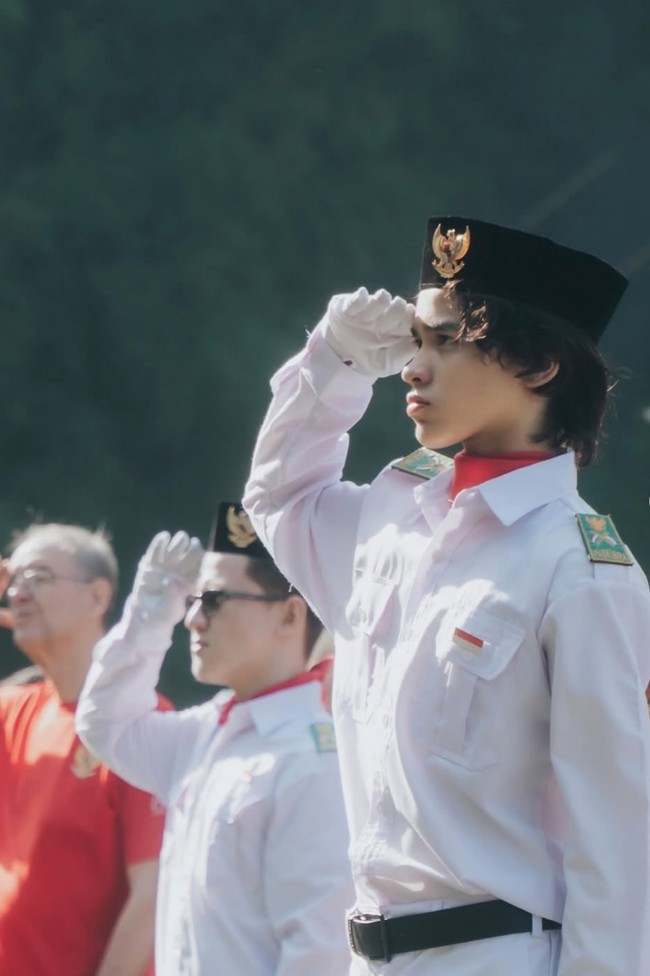 Diketahui upacara tersebut dilaksanakan di sekolah Noah, AIS, pada Jumat (15/8/25). Meski diterpa teriknya sinar matahari namun Noah tetap serius mengikuti jalannya upacara. Foto: Instagram/@itsmebcl