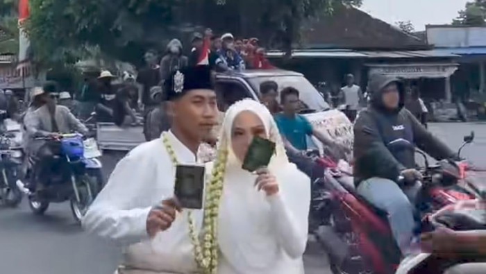 Tangkapan layar momen pasangan pengantin foto berlatar massa demonstran Bupati Pati.