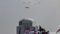 Helikopter TNI membawa bendera Merah Putih raksasa.