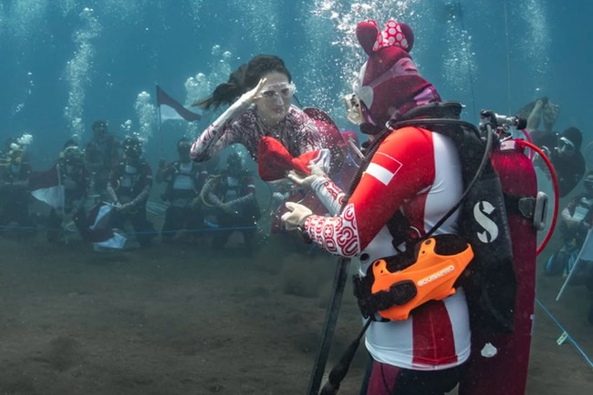 Mengenakan kostum putri duyung bernuansa merah-putih, Sherly melakukan freediving sambil membawa bendera. Foto: Instagram/@s_tjo