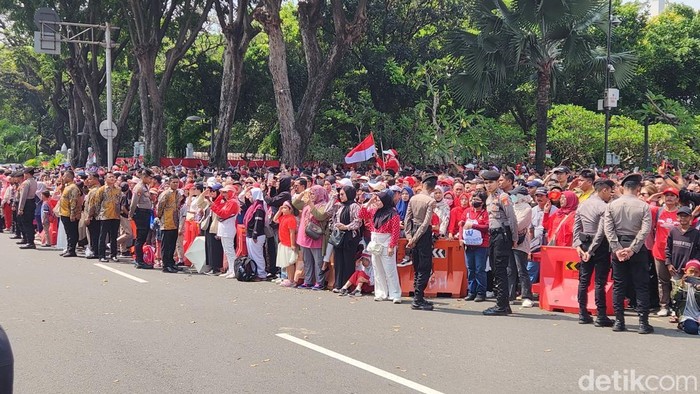 Masyarakat di depan Istana terlihat sikap sempurna dan kompak hormat saat pengibaran bendera Merah Putih di Istana. (Adrial/detikcom).