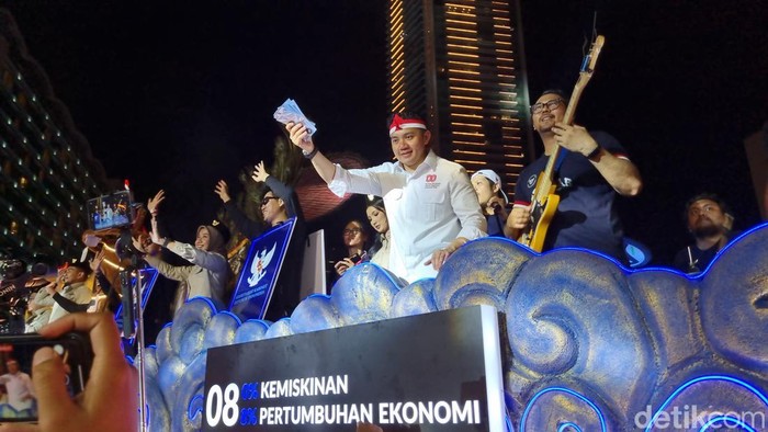 Menteri Sekretaris Kabinet (Seskab) Teddy Indra Wijaya membagikan hadiah saat karnaval peringatan HUT RI ke-80 di Bundaran HI. (Taufiq S/detikcom)