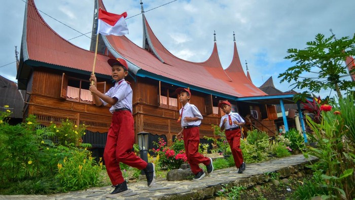 Sejumlah pelajar membawa bendera merah putih usai mengikuti upacara di kawasan Saribu Rumah Gadang Solok Selatan, Sumatera Barat, Minggu (17/8/2025). Yayasan Uma Nusantara menggelar upacara bendera HUT ke-80 RI bersama 80 peserta dari berbagai daerah di Indonesia dan juga melibatkan masyarakat setempat. ANTARA FOTO/Iggoy el Fitra/bar