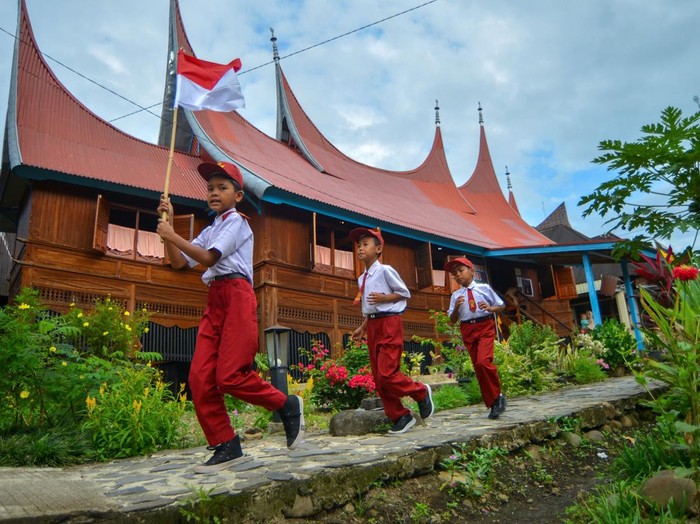 Sejumlah pelajar membawa bendera merah putih usai mengikuti upacara di kawasan Saribu Rumah Gadang Solok Selatan, Sumatera Barat, Minggu (17/8/2025). Yayasan Uma Nusantara menggelar upacara bendera HUT ke-80 RI bersama 80 peserta dari berbagai daerah di Indonesia dan juga melibatkan masyarakat setempat. ANTARA FOTO/Iggoy el Fitra/bar