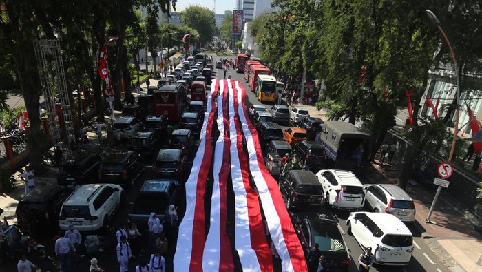 Pelajar SMA Negeri 6 dan SMA Trimurti Surabaya memberntangkan Bendera Merah Putih di jalan Gubernur Suryo, Surabaya, Jawa Timur, Minggu (17/8/2025). Aksi pembentangan bendera Merah Putih dengan total panjang 14.905 meter secara serentak oleh 10.868 pelajar SMA dan SMK tersebut tercatat dalam Museum Rekor Dunia Indonesia (MURI) untuk kategori pembentangan rangkaian kain merah putih dengan pelajar terbanyak. ANTARA FOTO/Moch Asim/sgd
