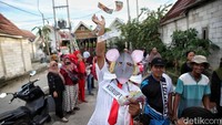 Para orang tua dan warga sekitar pun tidak ketinggalan memberikan dukungan. Mereka berjejer di pinggir jalan, bertepuk tangan, dan mengabadikan momen langka ini dengan kamera ponsel.