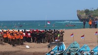 Pengibaran bendera dilakukan oleh tiga personel dari Sat Linmas Rescue Istimewa Wilayah Operasi II Pantai Baron, disusul rescue wilayah lain. Adapun untuk peserta upacara menyaksikan proses tersebut dari tepi pantai. (Foto: Jalu Rahman Dewantara/detikJogja)