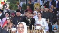 Nagita Slavina yang sedang memegang ponselnya langsung tersenyum saat kamera menyorotnya. Nagita Slavina mendampingi suaminya, Raffi Ahmad yang menjabat sebagai Utusan Khusus Presiden Bidang Pembinaan Generasi Muda dan Pekerja Seni. Mereka kompak memakai baju adat Jawa. Foto: Channel YouTube Sekretariat Presiden
