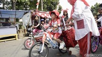 Peserta pawai mengenakan busana unik dan membawa kendaraan yang sudah dihias warna-warni.