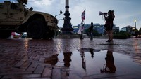 Seorang perempuan terlihat bernyanyi dengan pengeras suara di samping kendaraan militer, mengekspresikan kebebasan di tengah suasana pengamanan ketat. REUTERS/Alexander Drago