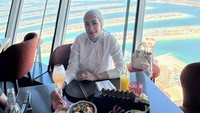 Erin Taulany lagi makan di gedung pencakar langit dengan memakai kemeja putih. Tasnya berwarna senada dengan kemejanya dan ada gantungan Labubu. (Foto: dok Instagram erintaulany)