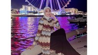 Erin Taulany lagi duduk di perahu memakai tunik lengan panjang dengan motif zig-zag warna-warni. Ia juga memakai celana panjang berwarna gelap dan jilbab yang cerah. (Foto: dok Instagram erintaulany)