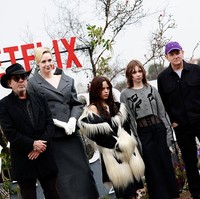 Jenna, yang disebut memiliki tinggi sekitar 155 cm, tampil dengan mantel bulu bergaya edgy. Di sebelahnya, Gwendoline Christie dengan postur 190 cm menjulang dalam balutan setelan blazer rapi. Foto: Getty Images for Netflix/James Gourley