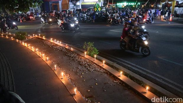 Warga menyalakan lilin dan tabur bunga di depan kantor Bupati Pati, Rabu (20/8/2025).