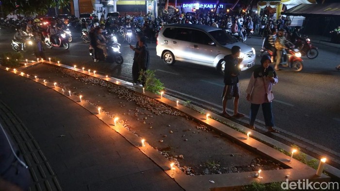 Warga menyalakan lilin dan tabur bunga di depan kantor Bupati Pati, Rabu (20/8/2025).
