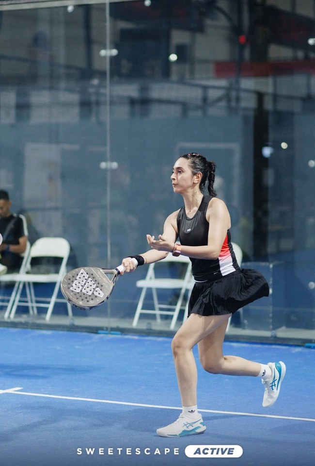 Nabila tampil kenakan tank top olahraga berwarna hitam dengan aksen garis merah dan putih di samping, memberi kesan sporty dan dinamis. Ia kemudian memadukannya dengan rok olahraga berwarna hitam model pleats, yang memberi tampilan feminin. Foto: Instagram/@nsyakieb85