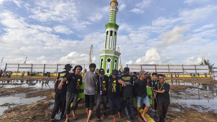 Petugas bersama warga membawa menara adat menjelang pelaksanaan tradisi mandi safar di Air Hitam Laut, Tanjung Jabung Timur, Jambi, Selasa (19/8/2025). Tradisi mandi safar yang berangkat dari kebiasaan masa lalu masyarakat pesisir setempat untuk menolak bala itu dilaksanakan setiap Rabu terakhir di bulan Safar atau jatuh pada 20 Agustus 2025. ANTARA FOTO/Wahdi Septiawan/foc.