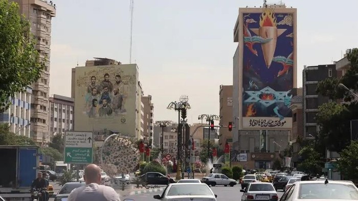 Traffic flows past a huge billboard bearing a painting of a missile falling on Israel with the slogan in Farsi: “The missile has fallen amidst the demons,” on a main road in central Tehran on July 16, 2025. (AFP)