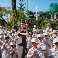 Riasan wajah tampak natural namun tetap tegas, dengan alis rapi, lipstik lembut, serta complexion wajah yang flawless. Dengan penuh semangat Yuni memimpin upacara untuk para murid sekolahnya yang berusia antara 4 hingga 6 tahun. Foto: Instagram/@yunishara36