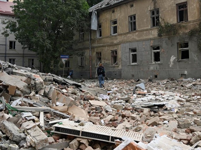 A person walks past a residential building damaged following Russian air attacks in the western Ukrainian city of Lviv on August 21, 2025, amid the Russian invasion of Ukraine. Russia launched hundreds of drones and missiles at Ukraine overnight, the Ukrainian air force said on August 21, 2025, Moscows largest attack in weeks after US-led efforts to halt the Kremlins invasion. (Photo by YURIY DYACHYSHYN / AFP)