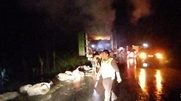 Petugas kepolisian bersama warga sekitar memadamkan api mobil yang terbakar