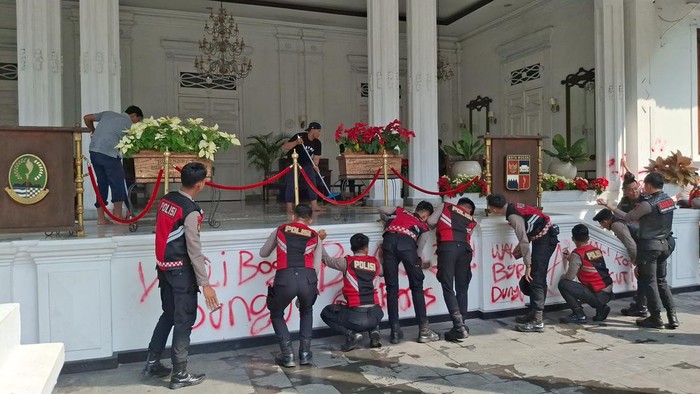 Anggota Polresta Bogor membersihkan vandalisme di Gedung Balai Kota Bogor.
