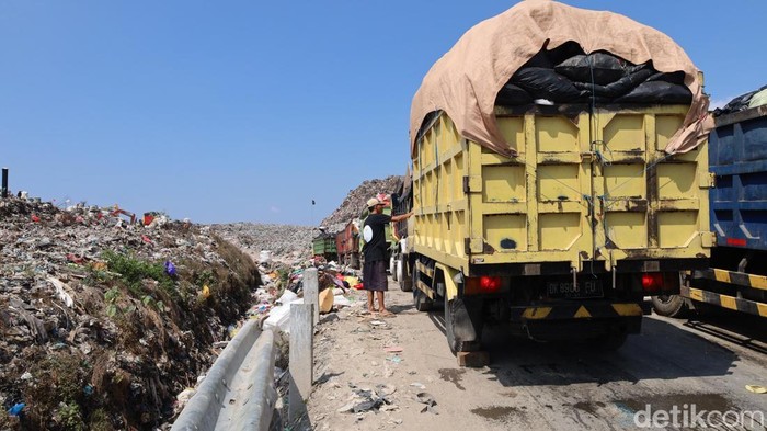 Barisan truk mengular dari Pura Dalem Pangararungan, UPT Timbang hingga ke TPA Suwung, Jumat (21/8/2025). (Aryo Mahendro/detikBali)