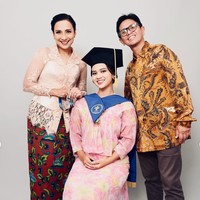 Di balik jubah toga wisudanya Charlotte terlihat mengenakan dress bermootif bunga dengan dominasi warna pink pastel bercampur kuning. Penampilannya dilengkapi dengan stocking dan heels pendek berwarna merah marun. Foto: Instagram/@shahnaz.haque/@charlotteramadhan