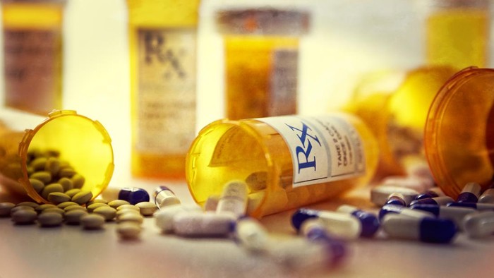 Group of medical prescriptions bottles and pills on white.