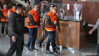Para tersangka kemudian digiring sejumlah pegawai KPK menuju ruang konferensi pers. Tangan mereka tampak diborgol sebagai bagian dari prosedur penahanan.  