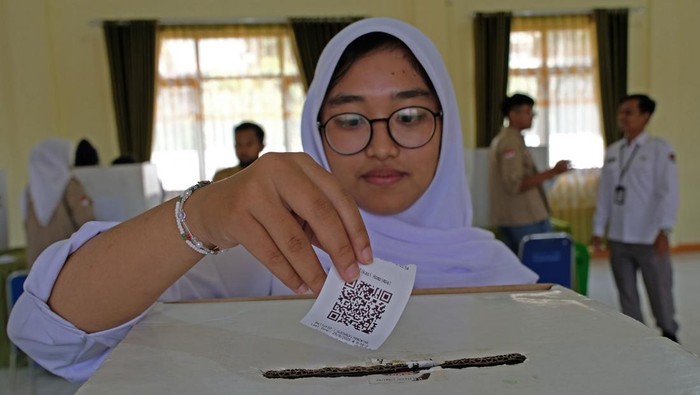 Seorang siswa memasukkan QR code surat suara ke dalam kotak saat e-voting pemilihan ketua OSIS di SMA Negeri 2 Temanggung, Jawa Tengah, Senin (25/8/2025). Kegiatan pembelajaran demokrasi dengan memanfaatkan teknologi terkini yang difasilitasi oleh KPUD Temanggung tersebut untuk mengajak pemilih pemula menggunakan hak pilihnya pada pilkada maupun pemilu mendatang. ANTARA FOTO/Anis Efizudin/nym.