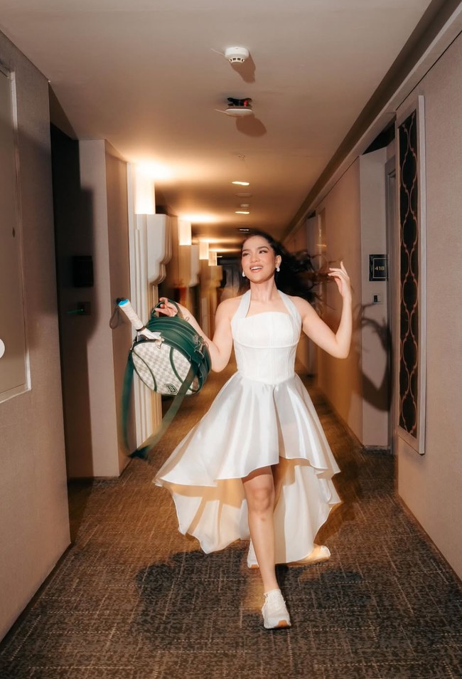 Alih-alih memakai heels, Davina memilih sneakers putih. Perpaduan ini memberi nuansa sporty. Sesuai dengan tema perayaan ulang tahunnya, Davina juga membawa tas hijau yang berisi raket padel. Foto: Instagram/@davinaakaramoy