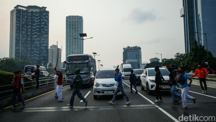 Massa Demo DPR Tutup Tol - Rusak Mobil Plat Merah Sejumlah massa aksi menutup ruas Tol Dalam Kota arah Semanggi di Flyover Pejompongan, Jakarta, Senin (25/8/2025).
