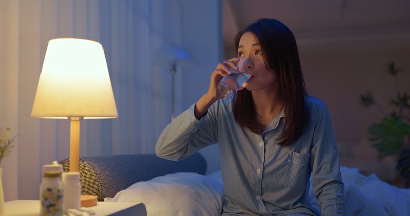 closeup asain woman take medicine before going to bed - she need to take sleeping pills