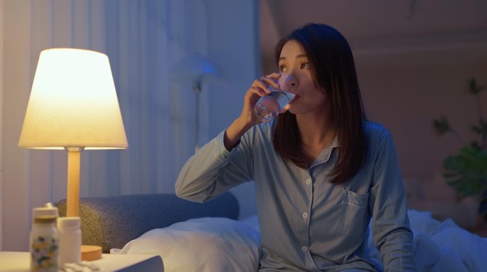 closeup asain woman take medicine before going to bed - she need to take sleeping pills