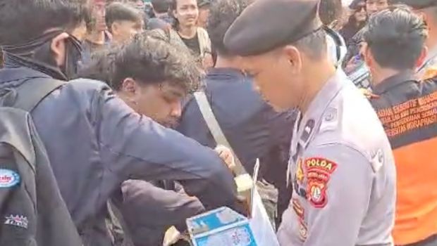 Polisi membagikan air mineral kepada pendemo di Senayan, Jakarta Pusat, Senin (15/8/2025).