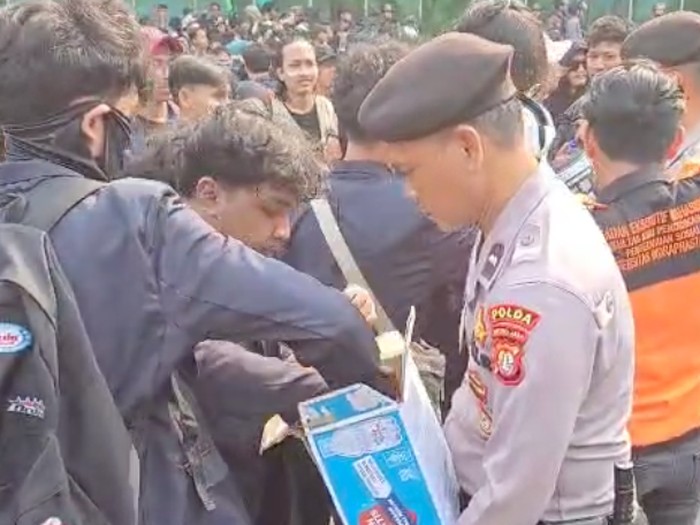 Polisi membagikan air mineral kepada pendemo di Senayan, Jakarta Pusat, Senin (15/8/2025).