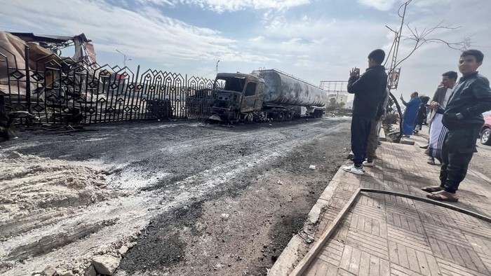 Pom Bensin Hancur dan Truk Terbakar Usai Serangan Udara Israel di Sanaa People stand outside a fuel station one day after it was hit by Israeli airstrikes in Sanaa, Yemen August 25, 2025. REUTERS/Stringer