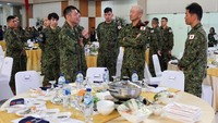 Prajurit Jepang tampak berkumpul mengikuti prosesi upacara, sementara tentara Australia dan Indonesia saling berjabat tangan sebagai simbol persahabatan dan kerja sama. Super Garuda Shield sendiri dikenal sebagai salah satu latihan militer terbesar di kawasan Indo-Pasifik. REUTERS/Willy Kurniawan