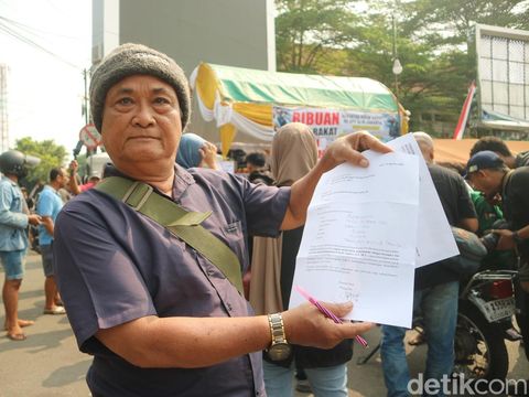 Warga di depan posko donasi Masyarakat Pati Bersatu menunjukkan surat yang akan dikirim ke KPK, Senin (25/8/2025).