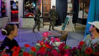 Anggota Garda Nasional AS dari Ohio membawa senjata saat berpatroli melewati pengunjung restoran di kawasan Logan Circle, Washington, D.C., Minggu (24/8/2025). Patroli bersenjata ini menuai kritik karena dianggap menimbulkan rasa takut. REUTERS/Brian Snyder 